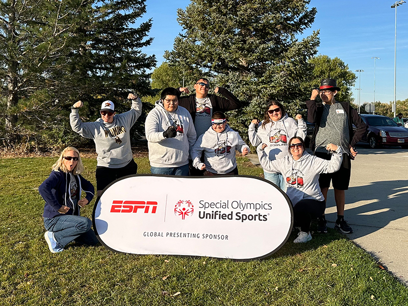 Happy students and teacher in front of ESPN Special Olympics sign