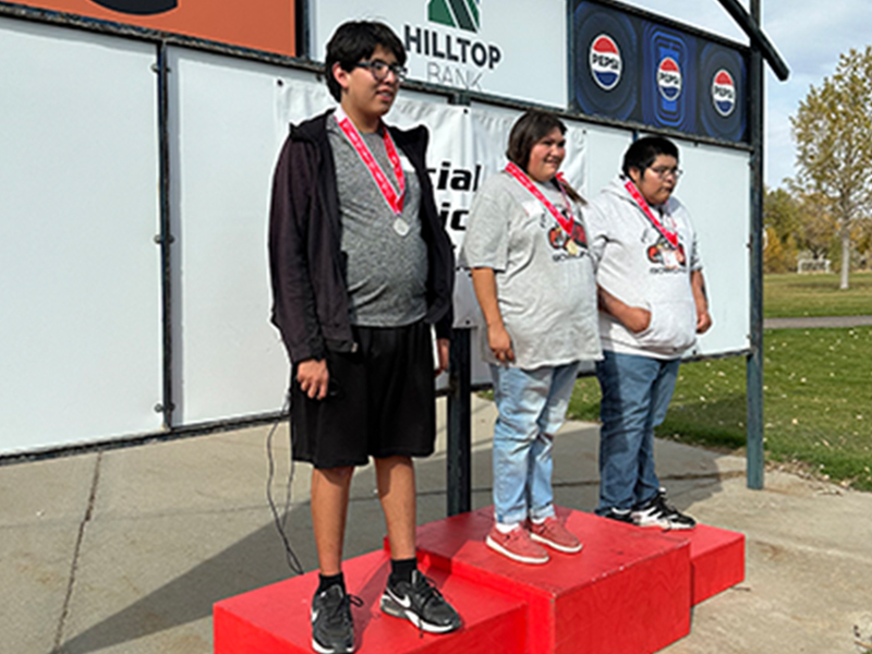 Three proud students receiving awards on the podium