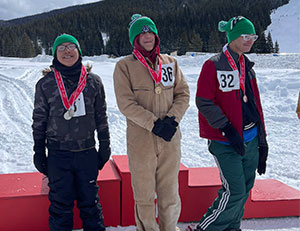 Three students wearing medals and snow shoes in the mountains