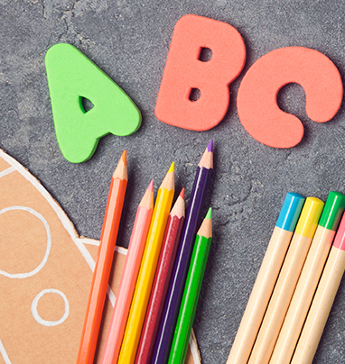 ABC, paper rocket, and colored pencils on a table