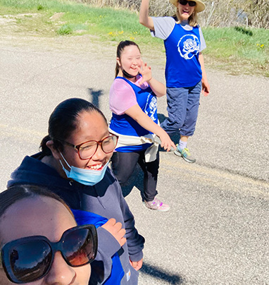 students and staff walking down the road smiling and waving to the camera