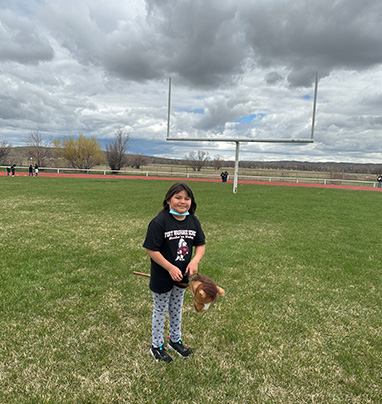 girl in field riding a stick pony