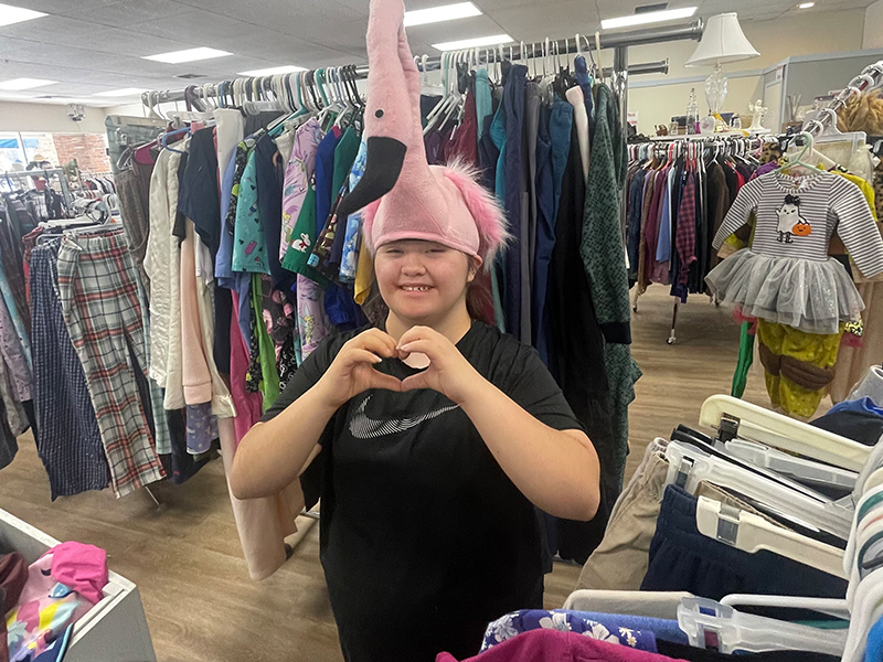 Student wearing a bird hat making heart-shape with hands