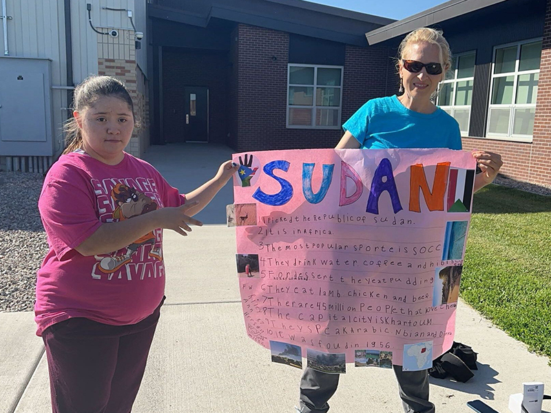 Woman and student holding up a SUDAN project poster