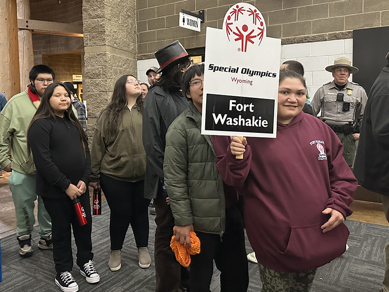 Group of athletes lead by woman holding Fort Washakie sign